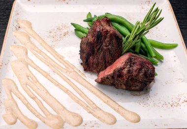 Filet mignon with asparagus on a light plate, on a dark background