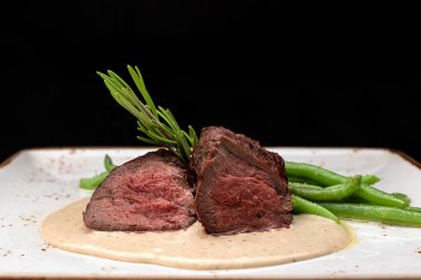 Filet mignon with asparagus on a light plate, on a dark background