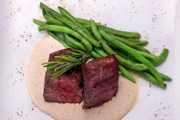 Filet mignon with asparagus on a light plate, on a dark background