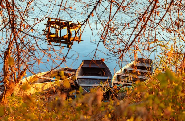 Tarde de otoño en una orilla desierta del río con un viejo puente de pesca y tres barcos de pesca. Nadie. — Foto de Stock