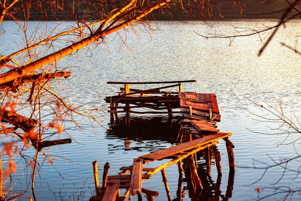 Serata autunnale su una riva deserta del fiume con un vecchio ponte di pesca. nessuno — Foto Stock