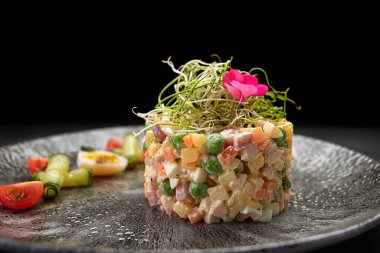 Olivier salatası gri güzel bir tabakta, koyu bir arka planda. Restoran servisi