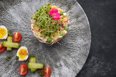 Olivier salatası gri güzel bir tabakta, koyu bir arka planda. Restoran servisi