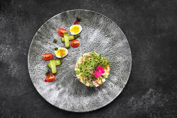 Olivier salatası gri güzel bir tabakta, koyu bir arka planda. Restoran servisi