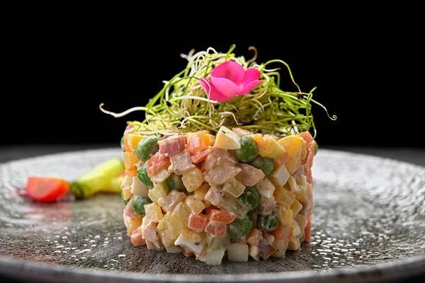 Olivier salatası gri güzel bir tabakta, koyu bir arka planda. Restoran servisi