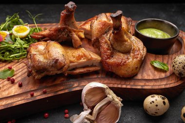 Tahtaya otlar ve sosla ızgara piliç. Siyah bir arkaplanda