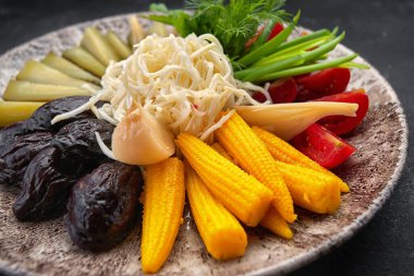 Koyu arkaplanda sebze turşusu salatalık domates otları.