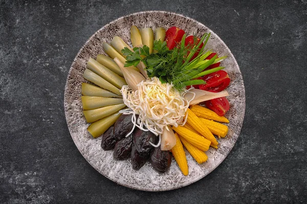 Verduras en vinagre sobre un fondo oscuro pepinos tomates hierbas Imagen de archivo