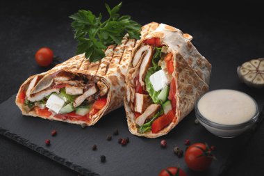 Soslu, domatesli ve peynirli leziz Yunan shawarması, menü ve reklam tasarımı için mükemmel sokak yemeği fotoğrafı.