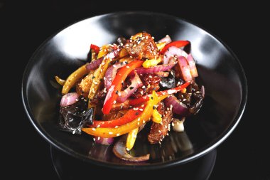 Siyah arka planda sebzeli baharatlı dana eti.