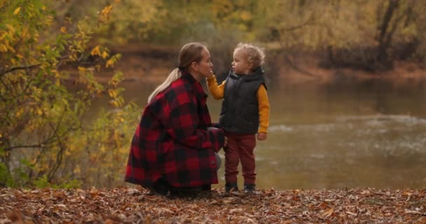 Спілкування матері і дитини на природі в лісі, жінка і її маленький син відпочивають на узбережжі ставка — стокове відео