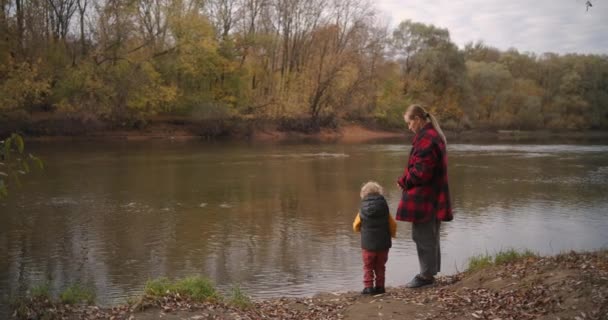 Fine settimana sulla riva del lago foresta in autunno, la giovane madre con il suo bambino sta guardando gli uccelli, trascorrendo del tempo con la famiglia — Video Stock