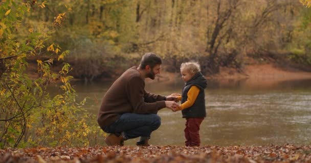 Loving father and little son are communicating at nature, on shore of lake at autumn day, man and boy are snuggling by foreheads — Stock Video