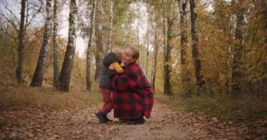 Anne ve küçük oğul sonbahar ormanlarında kucaklaşıyorlar, anne ve babanın şefkati ve şefkati doğada.