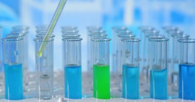 Bir laboratuarda, pipetli bir bilim adamı test tüplerindeki DNA ve molekülleri ayırmak için renkli bir sıvıyı analiz eder. Konsept: araştırma, biyokimya, doğa, ilaç
