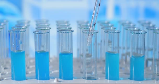 Σε ένα εργαστήριο, ένας επιστήμονας με πιπέτα αναλύει ένα χρωματιστό υγρό για να εξαγάγει το DNA και τα μόρια στους δοκιμαστικούς σωλήνες. Έννοια: έρευνα, βιοχημεία, φύση, φαρμακευτική ιατρική — Αρχείο Βίντεο