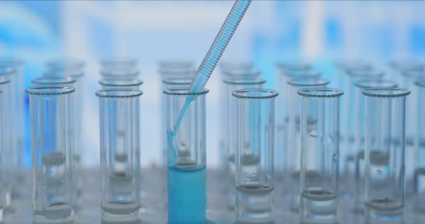 In een laboratorium analyseert een wetenschapper met een pipet een gekleurde vloeistof om het DNA en de moleculen in de reageerbuizen te extraheren. Onderwerp: onderzoek, biochemie, natuur, farmaceutische geneeskunde — Stockvideo