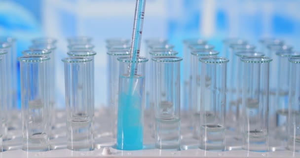 実験室では、ピペットを持った科学者が色のついた液体を分析し、試験管内のDNAや分子を抽出します。概念:研究、生化学、自然、医薬品 — ストック動画