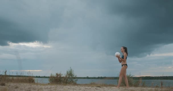 Smal ung kvinna hoppar och slår över bollen vid match av beachvolleyboll, slow-motion skott — Stockvideo