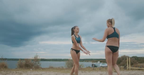 Два молодих пляжних волейболістки стикаються один з одним, відзначаючи бал на матчі — стокове відео