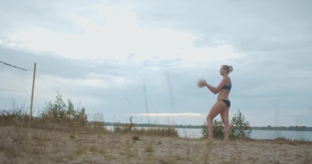 Jovem mulher esportiva está servindo bola na quadra de vôlei na praia, esporte de verão, treinamento e treino de atleta feminina — Vídeo de Stock