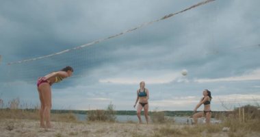 Plaj voleybolunun profesyonel bayan oyuncuları yaz tatilinde açık kumlu sahada yavaş çekimde oynuyorlar.