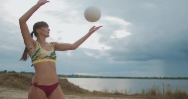 Sporcu kadın yaz günü plaj voleybolunda açık sahada top oynuyor, kadınlar voleybol oynuyor.