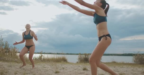 Спортивные женщины играют в пляжный волейбол летом, замедленные съемки против облачного неба днем — стоковое видео