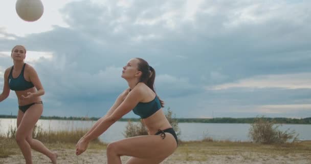 Esbeltas deportistas están jugando voleibol en la playa, tiro en cámara lenta de los jugadores de salto, pase y ataque — Vídeos de Stock