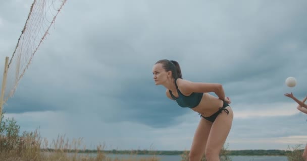 Tjäna och attackera i beachvolleyboll, match mellan två damer lag på öppen sandig bana på sommaren molnig dag, slow motion skott, mästerskap och träning — Stockvideo