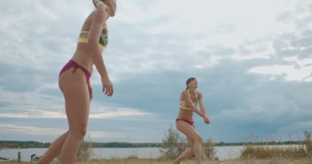 Unga kvinnor spelar volleyboll på stranden, professionella spelare tränar, hoppar och passerar bollen — Stockvideo