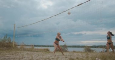 Plaj voleybolcularından oluşan profesyonel takım kadınlar kumlu sahada maç, dostça bir yarışma ve antrenman yapıyorlar.