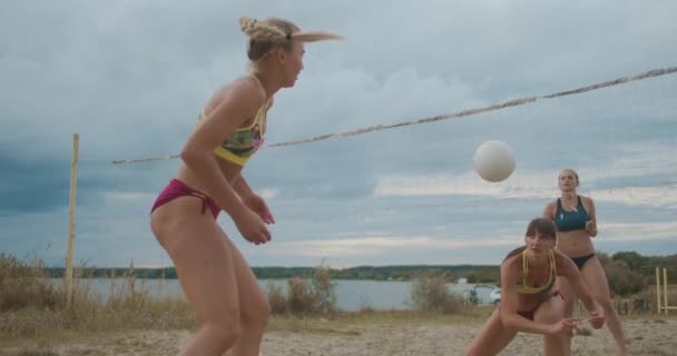Quatro mulheres vestidas de biquíni esportivo estão jogando vôlei de praia na quadra de areia no dia de verão, esporte e estilo de vida ativo — Vídeo de Stock
