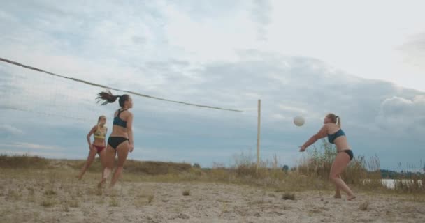 Mulheres estão jogando vôlei de praia em férias de verão, tiro em câmera lenta de saltar e correr atletas em quadra arenosa — Vídeo de Stock