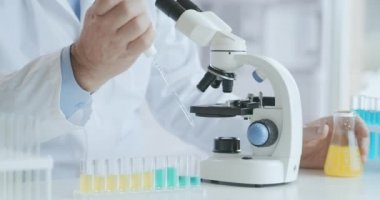 Sakallı beyaz erkek araştırmacı koruyucu gözlük takıyor ve mikroskop kapsülleriyle çalışıyor. Laboratuvarda mikroskop kullanan bir bilim adamı. Koronavirüs aşısı ara