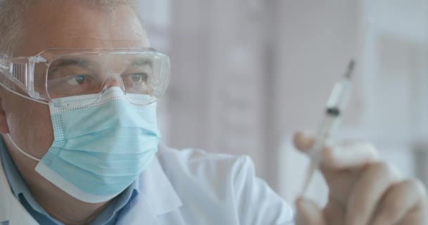 Medic Hands Voorbereiding van een spuit met Antibiotica voor Intraveneuze Behandeling. Een spuit met een geneesmiddel met een vaccin is in handen van een arts, het geneesmiddel wordt uit de spuit geperst, druppels — Stockvideo