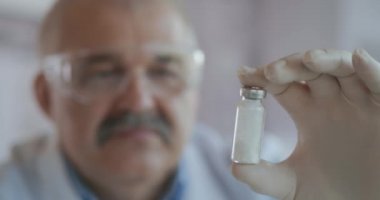 Bir eczacının elinde camdan ampuller içinde beyaz toz bulunan bir ilaç var. Virüslerle ve hastalıklarla savaşmak için yeni bir ilaç. Coronavirus için ilaç. Anestezi