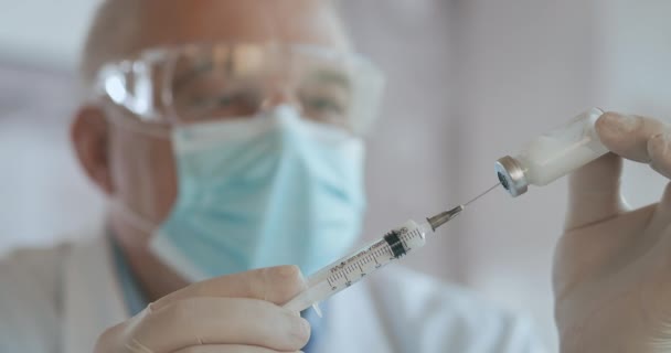 Dicht shot van onherkenbare verpleegkundige of arts in handschoenen die de spuit van ampul vullen met covid-19 vaccin. Zuster die injectiespuit vult uit injectieflacon. — Stockvideo