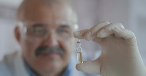 Um farmacêutico detém um medicamento em ampolas feitas de vidro. Uma nova droga para combater vírus e doenças. Medicina para o coronavírus — Vídeo de Stock