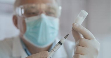 Tanımlanamayan hemşire ya da eldivenli doktorun şırıngayı covid-19 aşısıyla doldurduğu yakın çekim. Şırıngayı şişeden dolduran hemşire.