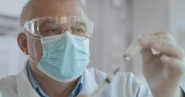 Doktor şırıngaya, şişeye, kovid 19 'a, koronavirüs ampulüne ve enjeksiyona aşı yapar. Tanımlanamayan hemşire ya da eldivenli doktorun şırıngayı covid-19 aşısıyla doldurduğu yakın çekim.