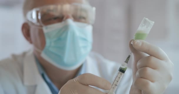 Doctor hand holds a syringe and a blue vaccine bottle at the hospital. Health and medical concepts. doctor draws vaccine to syringe, vial, covid-19, coronavirus ampoule, injection — Stock Video