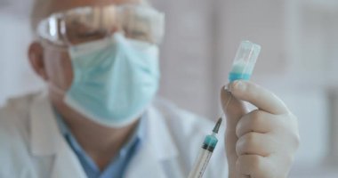 Tanımlanamayan hemşire ya da eldivenli doktorun şırıngayı covid-19 aşısıyla doldurduğu yakın çekim. Şırıngayı şişeden dolduran hemşire.