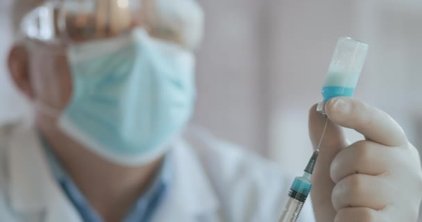 El médico extrae la vacuna a la jeringa, vial, covid-19, ampolla de coronavirus, inyección. Inyección cercana de enfermera o médico irreconocible en guantes que llenan la jeringa de ampolla con la vacuna covid-19 — Vídeo de stock