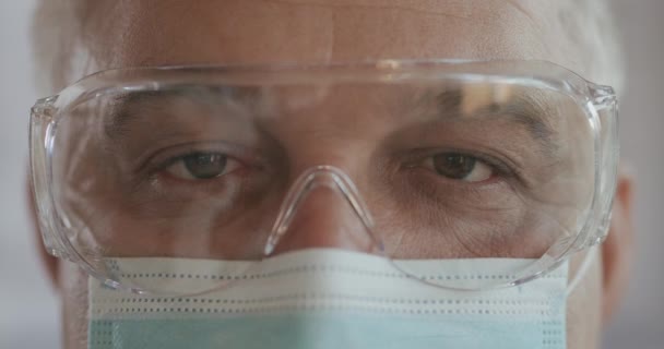 Kendine güveni tam bir doktor yüzü, yakın plan. Güvenlik gözlüklü ve koruyucu maskeli gözler. Araştırma laboratuvar memuru. 2019 Roman Coronavirus 2019-nCoV, salgın, izolasyon konsepti. — Stok video