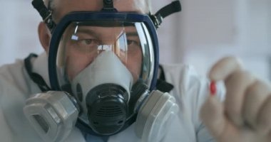 Bir ilaç şirketinde çalışan bir bilim adamı cam solunum cihazındaki bir laboratuvarda ilaç geliştiriyor. Yeni bir ilaç tutuyor. Kırmızı bir hap.