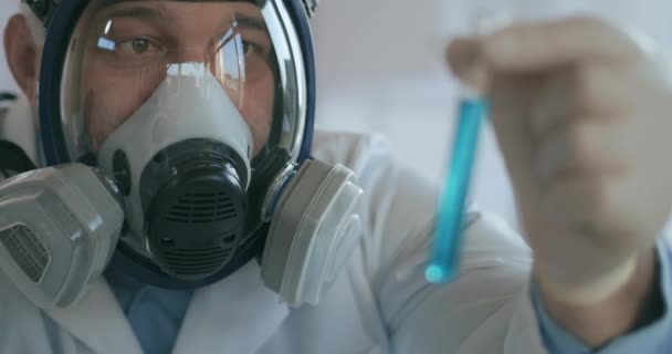 A male Professor examines a test tube with a blue solution with a virus Covid — Stock Video