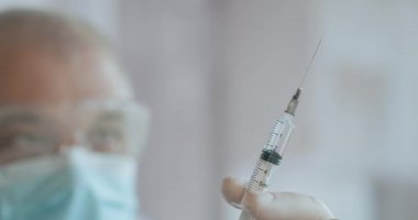 Medic Hands damar içi tedavi için antibiyotikle şırınga hazırlıyor. İçinde aşı olan bir şırınga bir doktorun elindedir. İlaç şırıngadan çıkarılır ve düşer.