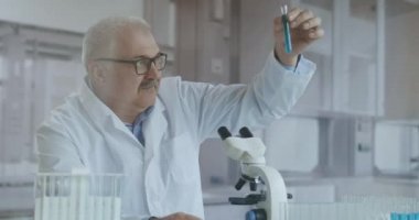 Laboratuvar. Mavi eldiven tüpleri hareket ettirir ve mavi sıvı damlatır. Test tüpünde sarı ve mavi sıvı numunesi tutan bir tıp çalışanı laboratuardaki idrarı analiz ediyor..