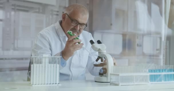 Científico investigador masculino. Se sienta en un laboratorio moderno de gama alta con vasos de precipitados, cristalería, microscopio y monitores de trabajo que lo rodean. — Vídeos de Stock